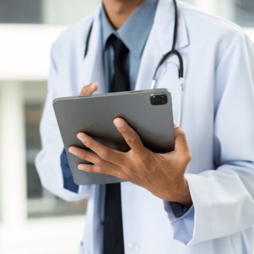 Médico com jaleco e estetoscópio segura um tablet, representando tecnologia e marketing digital aplicado à área da saúde.