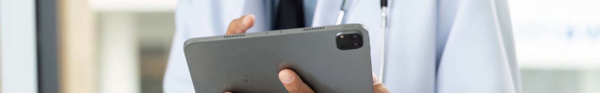 Médico com jaleco e estetoscópio segura um tablet, representando tecnologia e marketing digital aplicado à área da saúde.