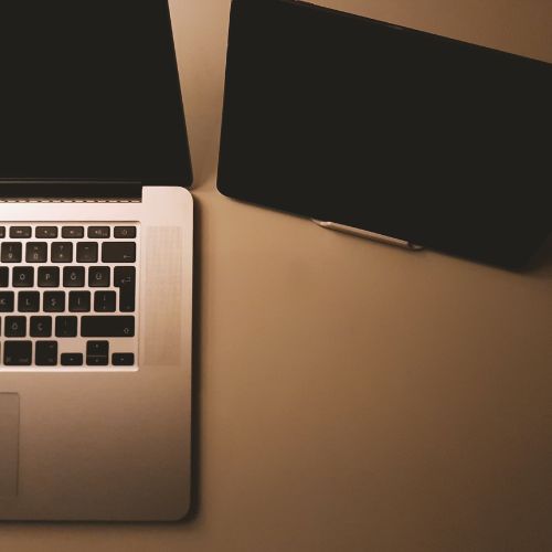 Foto de um notebook e um tablet sobre uma mesa em tom amadeirado, representando tecnologia, trabalho digital e criação de sites profissionais.