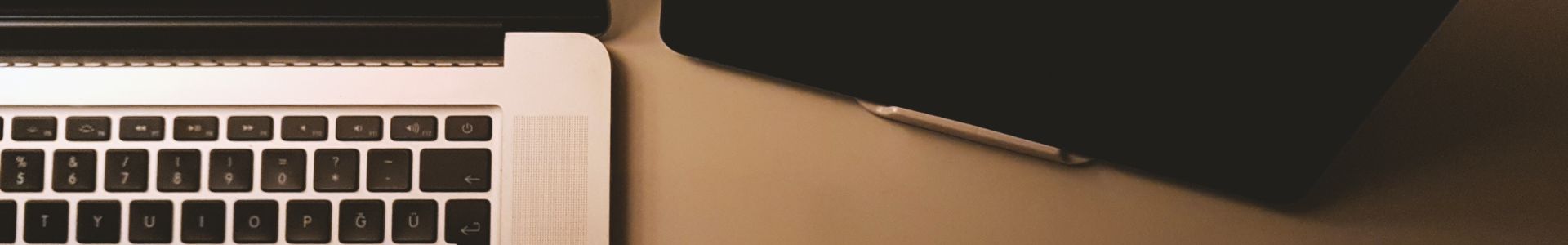 Foto de um notebook e um tablet sobre uma mesa em tom amadeirado, representando tecnologia, trabalho digital e criação de sites profissionais.