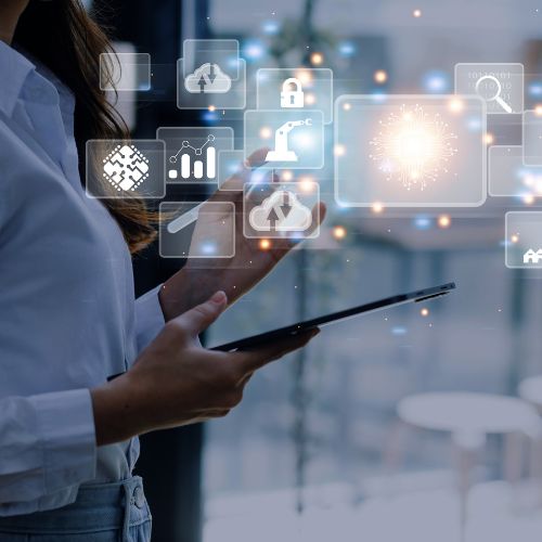 Pessoa usando tablet enquanto observa ícones digitais flutuantes que representam tecnologia, análise de dados e automação.