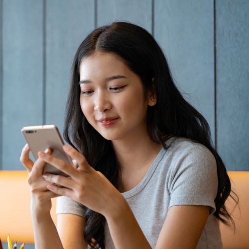 Mulher utilizando smartphone em ambiente interno, representando conexão digital e presença online.